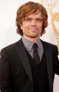 Peter Dinklage smiles to the camera at a red carpet Hollywood event, dressed in a suit and tie